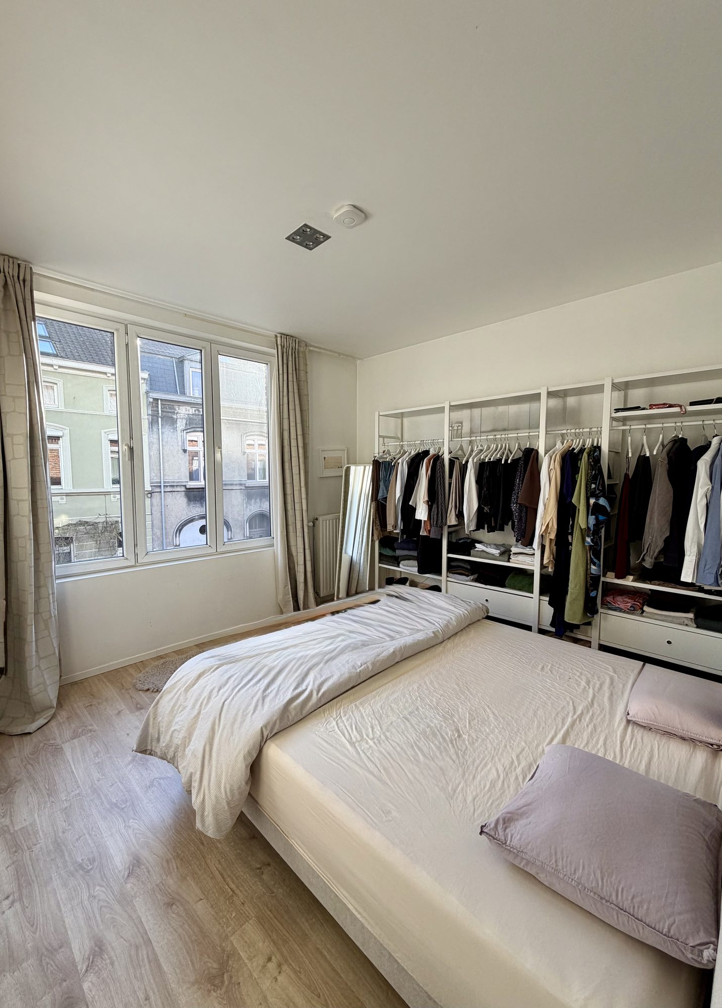 Master bedroom met groot raam, dressing en houten vloer